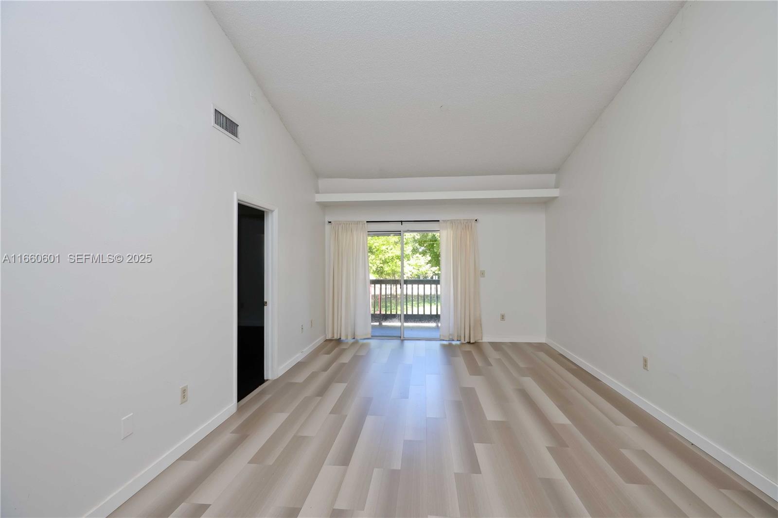 446 Southwest 113th Way, Unit 446 Pembroke Pines, FL 33025 - Photo 3 of 39 a view of an empty room with wooden floor and a window