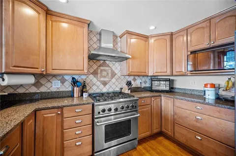 a kitchen with stainless steel appliances granite countertop a refrigerator a oven and a sink with wooden floor