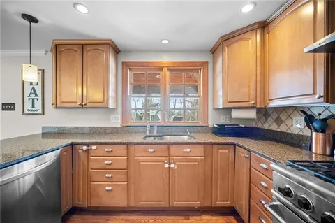 a kitchen with stainless steel appliances granite countertop a sink stove and wooden cabinets