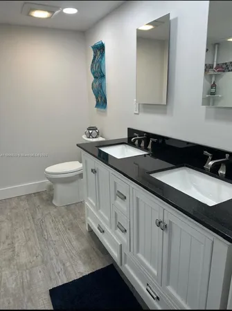 a bathroom with a granite countertop sink and a toilet