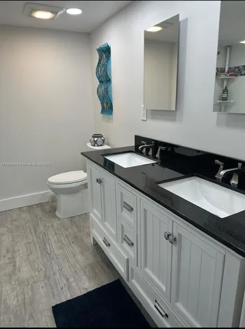 a bathroom with a granite countertop sink and a toilet