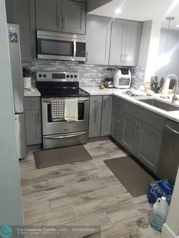 a kitchen with stainless steel appliances kitchen island granite countertop a sink stove and cabinets