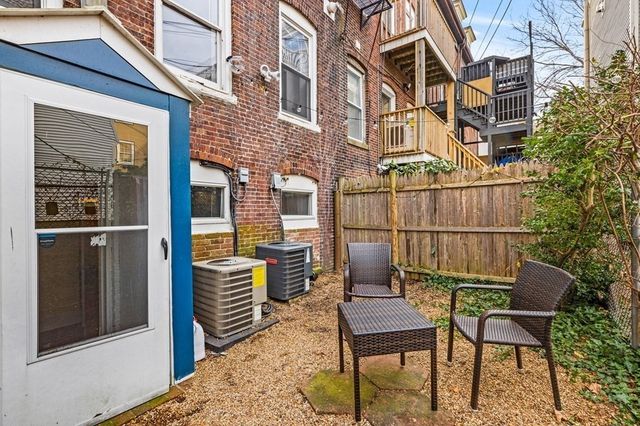 a backyard of a house with barbeque oven wooden table and chairs