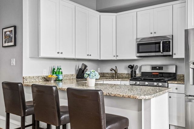 a kitchen with stainless steel appliances granite countertop a stove a sink a microwave and white cabinets