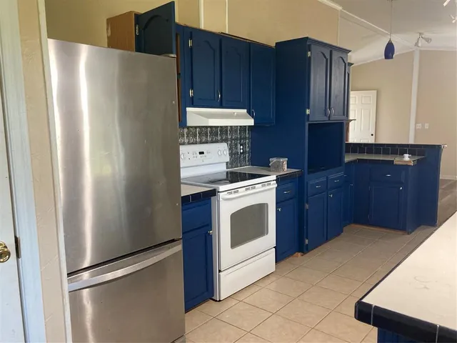 a kitchen with stainless steel appliances granite countertop a refrigerator a stove and a refrigerator