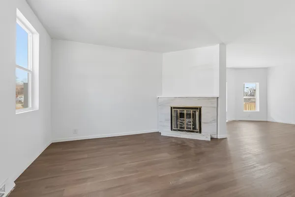 a view of an empty room with window and wooden floor