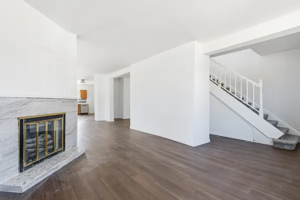 a view of an empty room with wooden floor and a fireplace