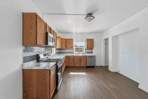 a kitchen with stainless steel appliances a sink cabinets and wooden floor