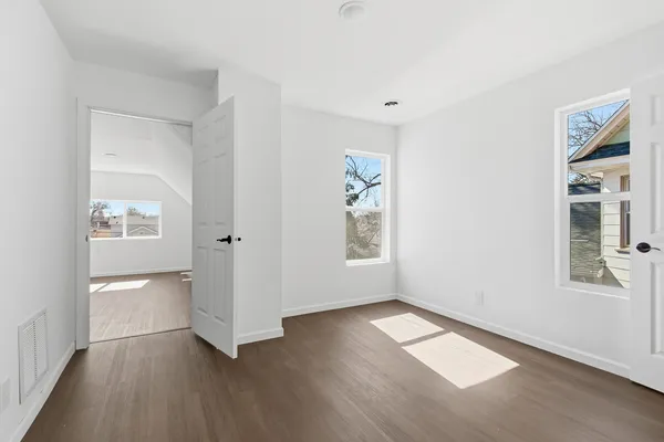 an empty room with wooden floor and windows
