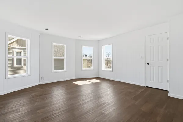 a view of an empty room with wooden floor and windows