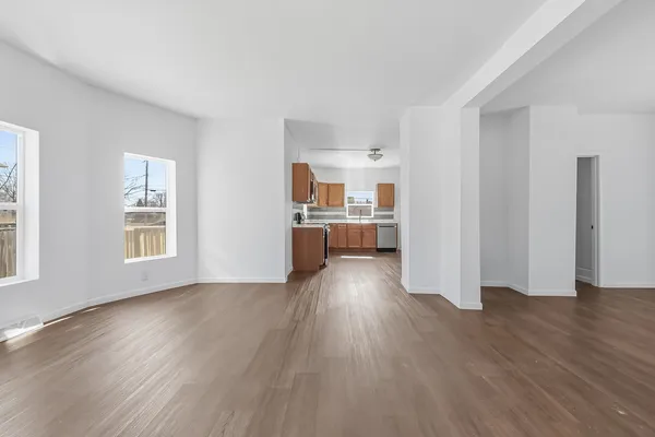 a view of a kitchen and an empty room with wooden floor and a kitchen