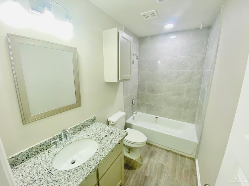 1105 West Kennedy Street, Unit 19 Pharr, TX 78577 - Photo 11 of 11 a bathroom with a granite countertop sink a toilet and bathtub
