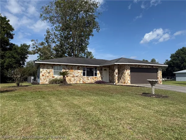 a front view of house with yard and trees in the background