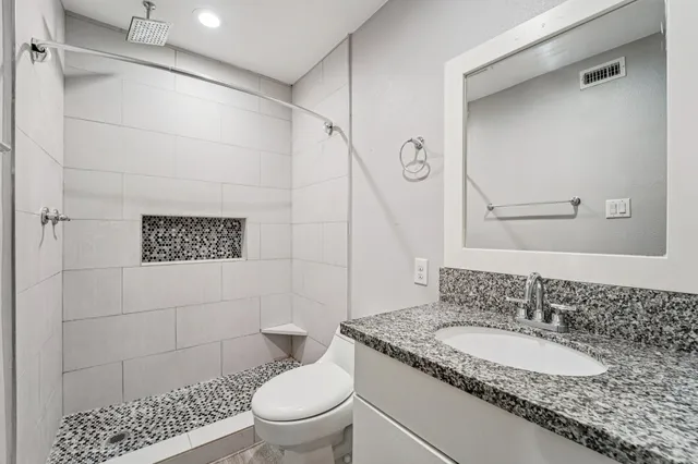 a bathroom with a granite countertop sink toilet and shower