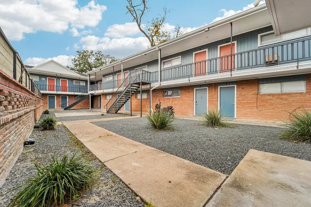a view of a white house with a yard and potted plants