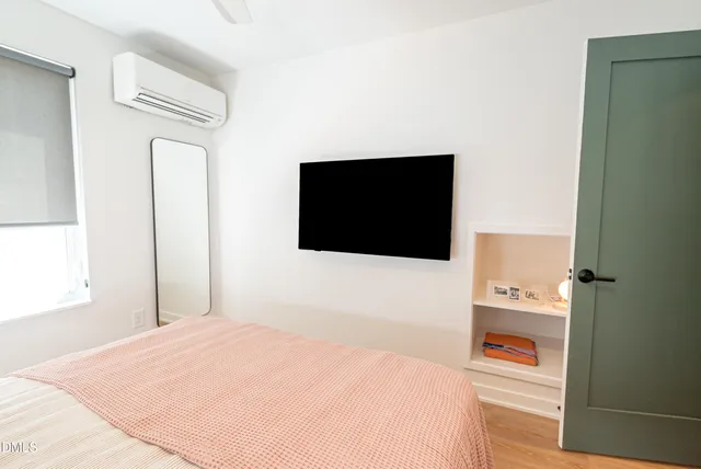 a bedroom with a bed and a flat tv screen next to a window