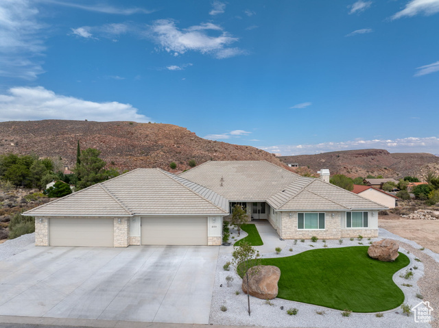 230 Boulder Way Leeds, UT 84746 - Photo 43 of 72 Ranch-style house featuring stone siding, a mountain view, an attached5+ car garage, concrete driveway, Low E WIndows, artificial turf & floral bushes.