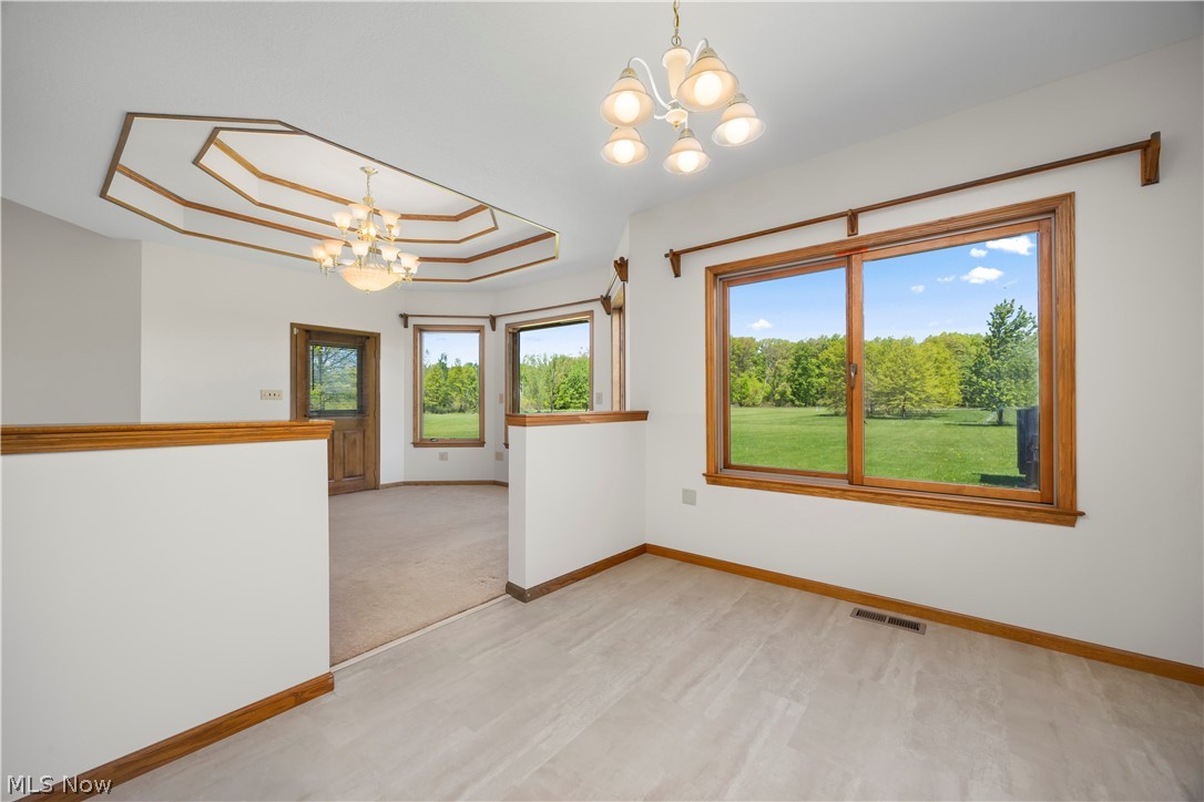 51488 Peck Wadsworth Road Wellington, OH 44090 - Photo 30 of 50 Bright interior featuring large windows, wood-finish trim, a decorative tray ceiling, and a chandelier lighting fixture