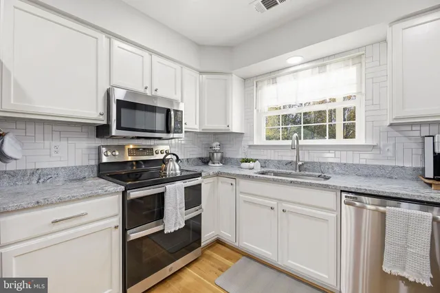 a large white kitchen with lots of counter space a sink and appliances