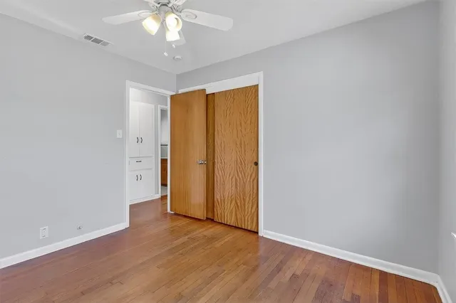 an empty room with wooden floor and a ceiling fan