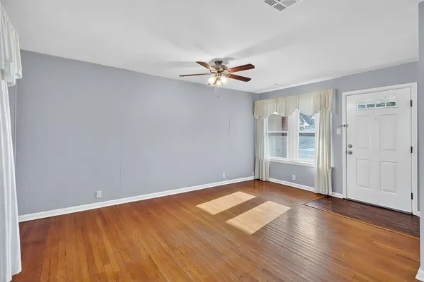 an empty room with wooden floor and windows