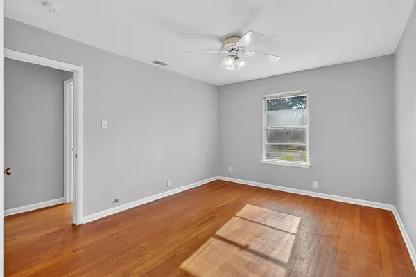 a view of an empty room with wooden floor and a window