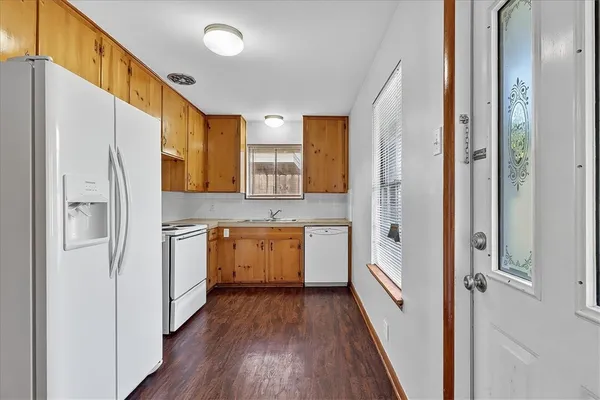 a kitchen with a refrigerator a sink and dishwasher with wooden floor