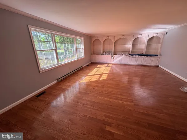 a view of an empty room with a window and wooden floor