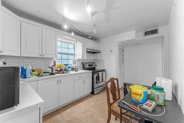 a kitchen with stainless steel appliances granite countertop a sink a stove a dining table and chairs with wooden floor