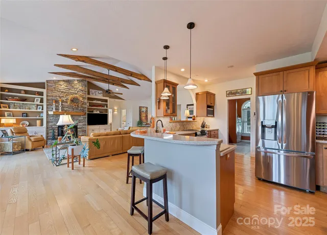 a kitchen with stainless steel appliances kitchen island granite countertop a refrigerator a stove and a wooden cabinets with wooden floor