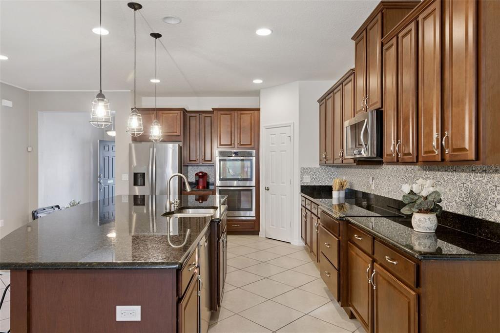 3940 Pine Gate Trail Orlando, FL 32824 - Photo 5 of 36 a kitchen with stainless steel appliances granite countertop a sink a stove and a refrigerator
