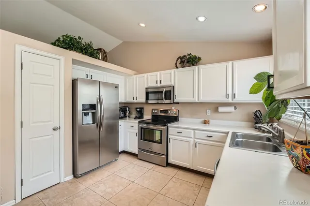 a kitchen with white cabinets stainless steel appliances and a potted plant