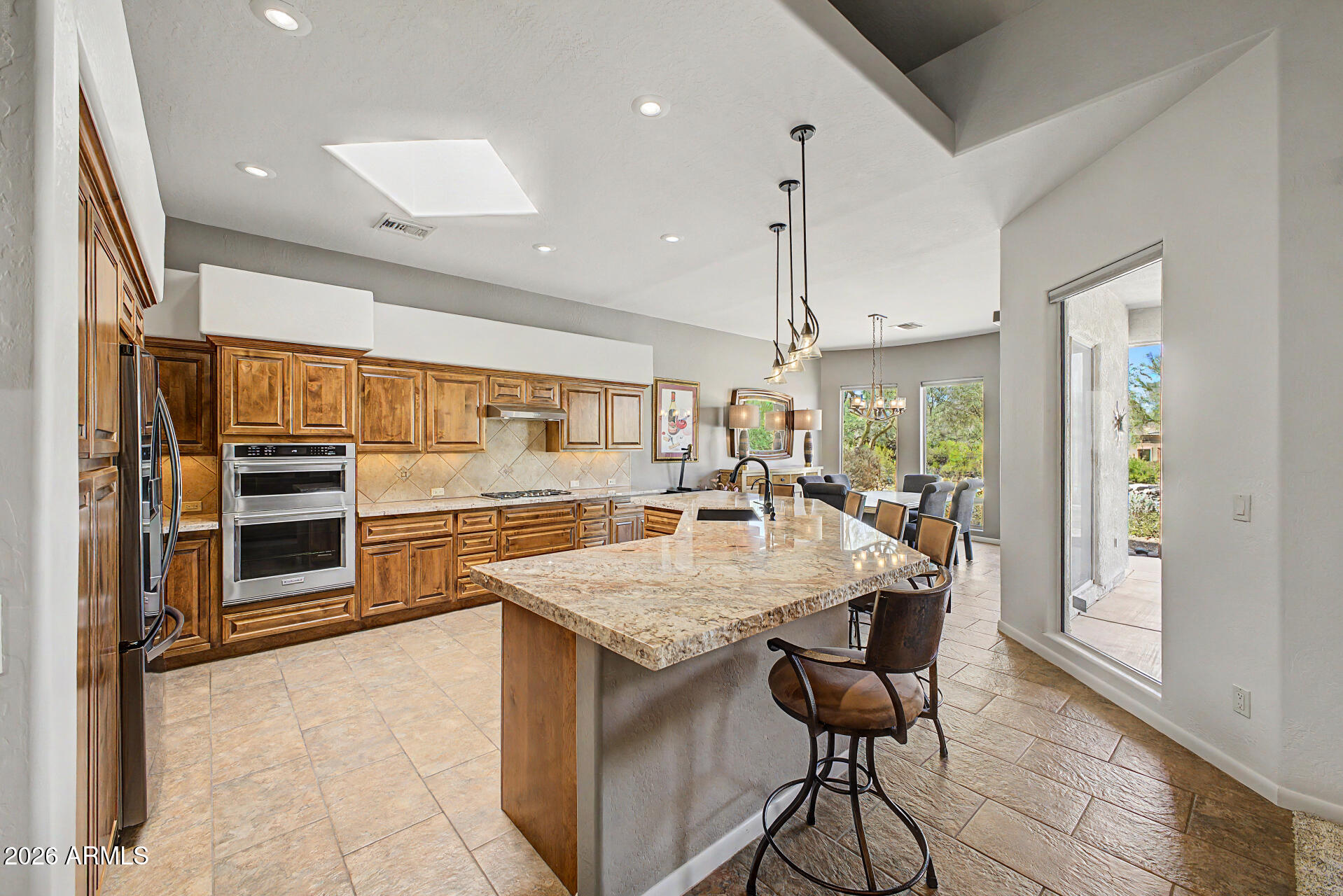 27909 North Quail Spring Road Rio Verde, AZ 85263 - Photo 12 of 52 a kitchen with stainless steel appliances kitchen island granite countertop a stove a refrigerator and a dining table with wooden floor
