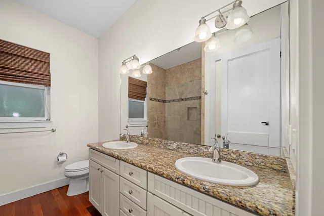 a bathroom with a granite countertop sink a mirror and shower
