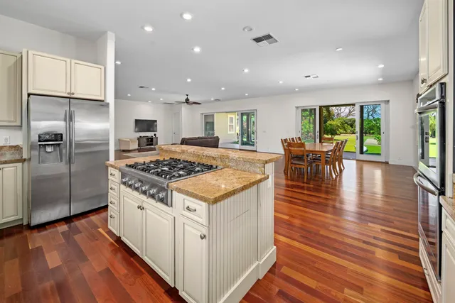 a kitchen with stainless steel appliances granite countertop a stove refrigerator and a dining table with wooden floor