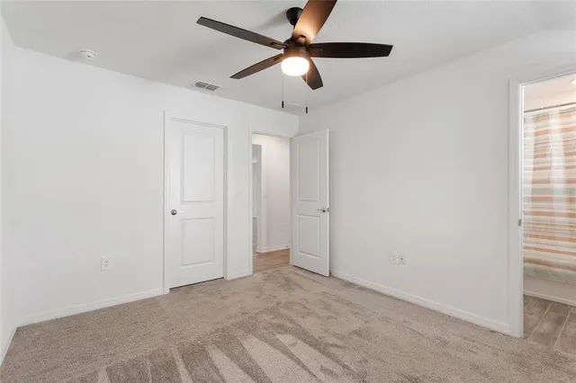 a view of an empty room and window with a fan