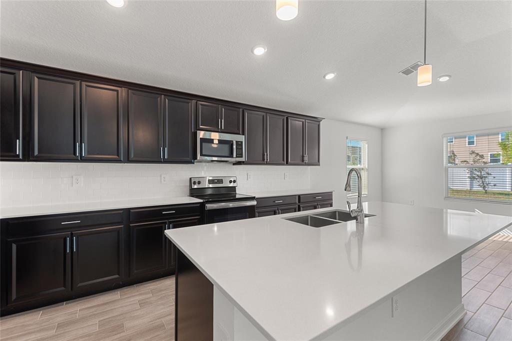 5767 Talc St Mount Mount Dora, FL 32757 - Photo 23 of 44 a kitchen with stainless steel appliances granite countertop a sink a stove and microwave
