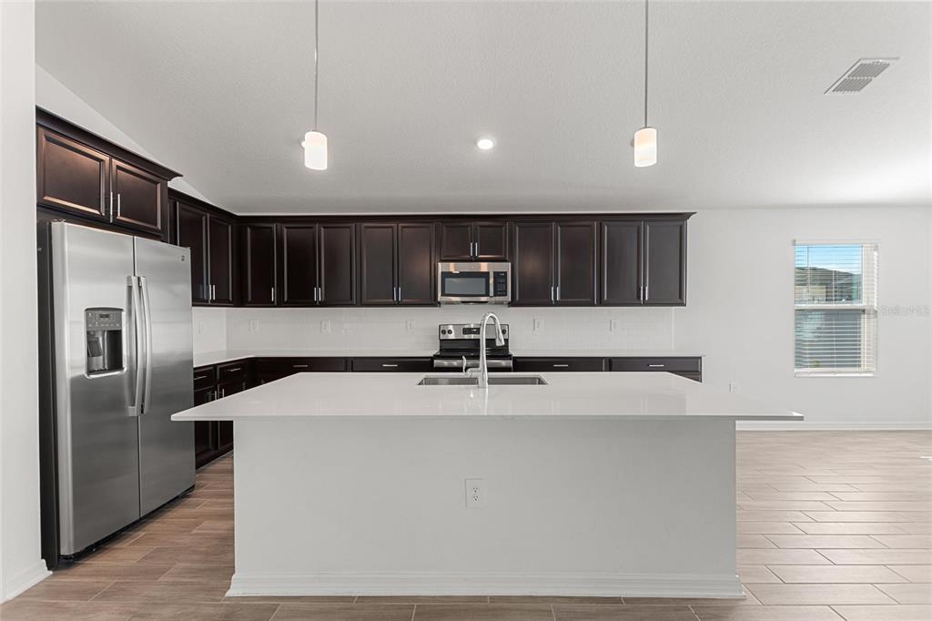 5767 Talc St Mount Mount Dora, FL 32757 - Photo 24 of 44 a view of a kitchen with stainless steel appliances granite countertop a refrigerator a sink and a stove