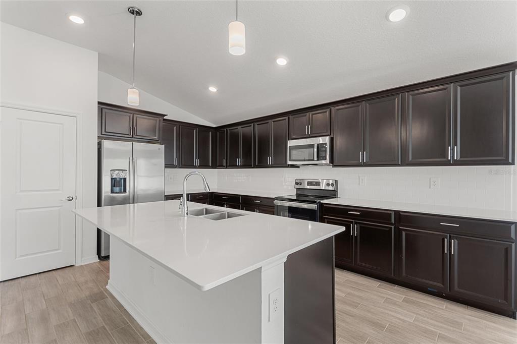5767 Talc St Mount Mount Dora, FL 32757 - Photo 25 of 44 a kitchen with stainless steel appliances a sink a stove a refrigerator cabinets and wooden floor