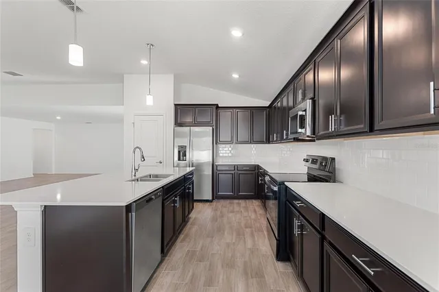 a kitchen with stainless steel appliances granite countertop refrigerator a sink a stove and wooden cabinets