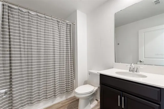 a bathroom with a granite countertop toilet a sink a mirror and a shower