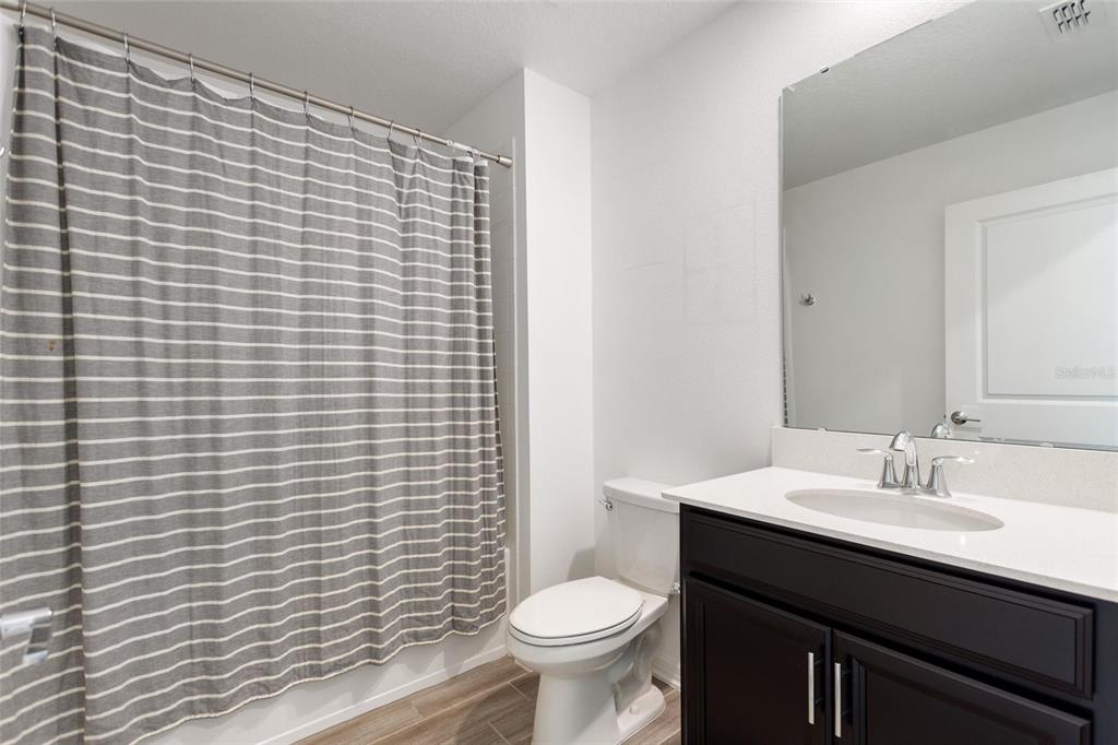 5767 Talc St Mount Mount Dora, FL 32757 - Photo 7 of 44 a bathroom with a granite countertop toilet a sink a mirror and a shower