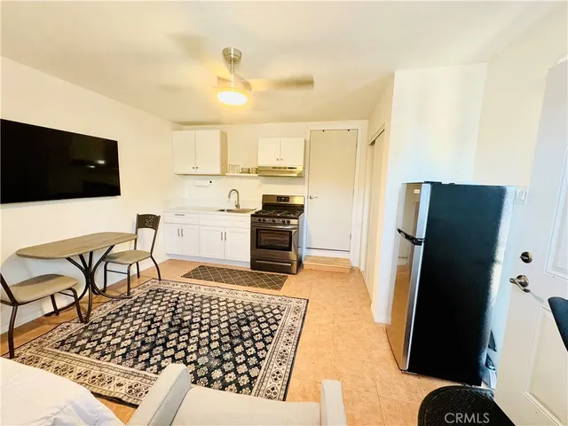 a living room with stainless steel appliances kitchen island granite countertop a refrigerator and a stove top oven