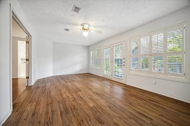 a view of an empty room with wooden floor and a window