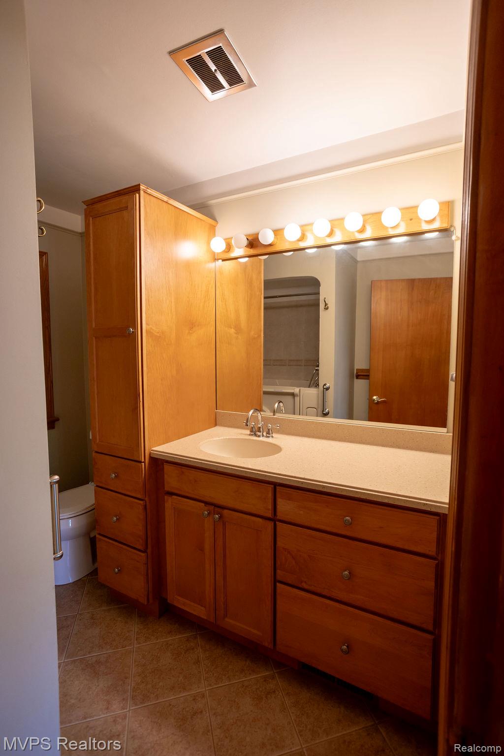 33033 Edgegrove Road Fraser, MI 48026 - Photo 15 of 20 Bathroom vanity featuring a light-toned countertop, integrated sink, and an extended mirror with vanity lighting