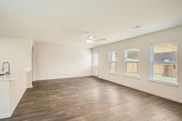 a view of an empty room with a window and wooden floor