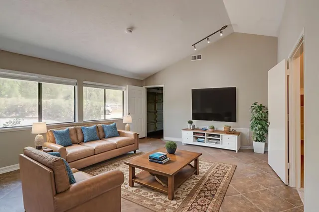 a living room with furniture a flat screen tv and a large window