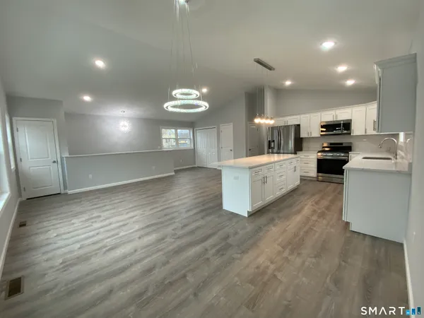 a large kitchen with stainless steel appliances a large counter top a sink a refrigerator and a stove