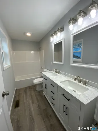 a bathroom with a granite countertop sink mirror and toilet