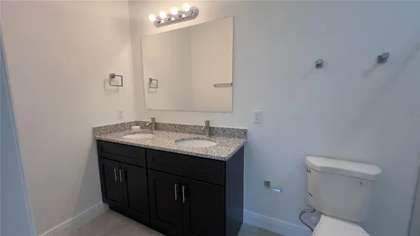 a bathroom with a granite countertop double vanity sink a mirror and a shower